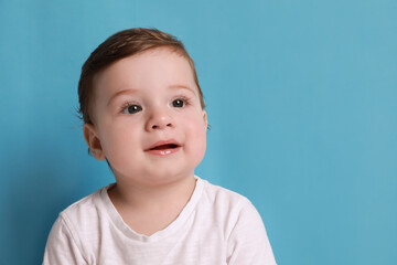 Cute little baby boy on light blue background, space for text