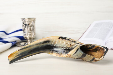 Shofar and other Rosh Hashanah holiday attributes on white wooden table