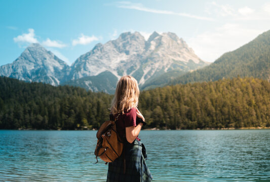 Young blonde woman stops to contemplate Blindsee lake with the Biberwierer Scharte in the background, alpine image in Austria, hiking and happiness in the alps. Backpacking and hiking in nature.
