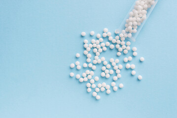 Homeopathy medicine alternative herbs. Homeopathic globules and glass bottle on a blue background. Health care and medicine concept.
