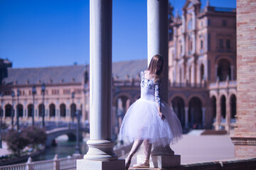 Obraz premium Adult female Hispanic classical ballet dancer making figures between two stone columns, wearing a white tutu.