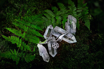 Clear crystals and witch wiccan amulet with pentagram on forest dark natural background. Esoteric...