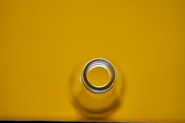 Photo of empty glass bottle. Yellow background.