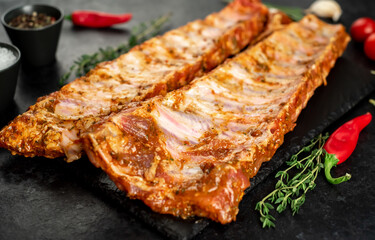 raw pork ribs marinated with spices on a stone background