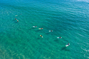 Surfers sit on their boards waiting for the waves in the blue sea, clear water.