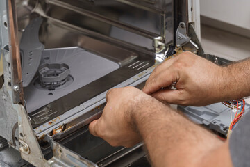 echnician or plumber repairing the dishwasher in a household. a man removes a damaged, dirty rubber seal for replacement.
