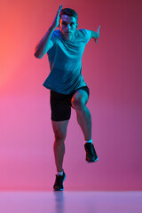 Portrat of Caucasian professional male athlete, runner training isolated on pink studio background...