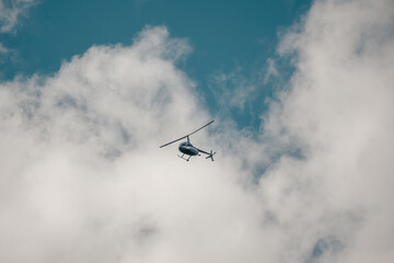 A small helicopter in a cloudy sky. Private flights, transportation of tourists.