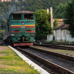 Naklejka premium A diesel locomotive with wagons passes near the station