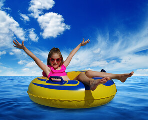 Obraz premium Little girl on inflatable ring in blue sea water
