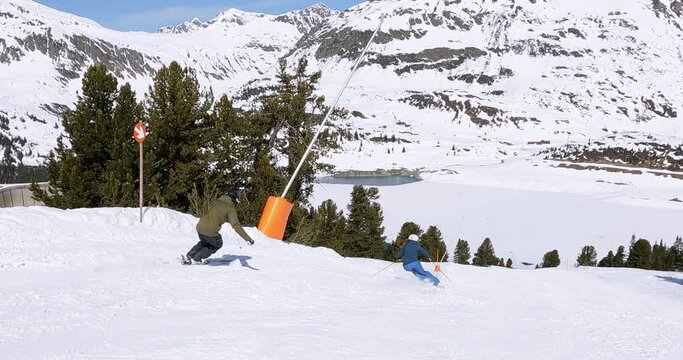 Rythmic skiing of a young femal and a male skier on a beautiful groomed ski slope in a ski resort in Tyrol. Ski show of ski friends with beautiful view on the alpine snowy mountains. 4K Follow camera