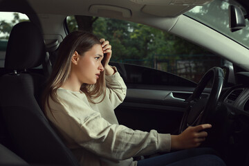 Fototapeta na wymiar Stressed young woman in driver's seat of modern car