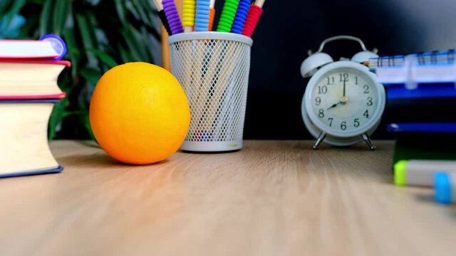 student home office table with white alarm clock, books, orange, colored notebooks, pencils in glass, chalk board, globe, white alarm clock, concept of education, back to school, knowledge day