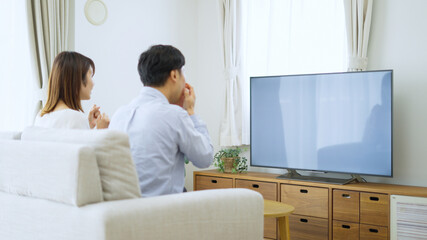 家でテレビを見る夫婦・カップル