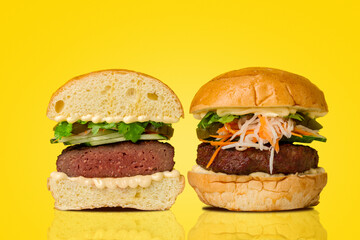 Burger cut in half on yellow background.  Two parts of burger. Hamburger. Cheeseburger. 