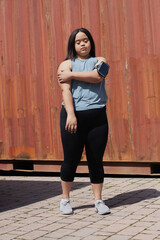 Young biracial woman with Down Syndrome in active wear and wearable tech stretching her arms