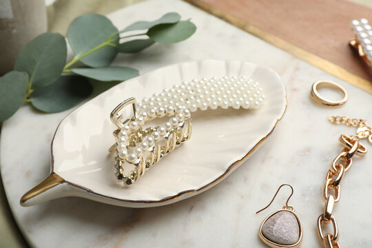 Stylish bijouterie and hair accessories on decorative board, closeup