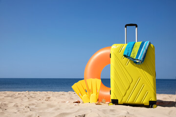 Suitcase and beach accessories on seaside. Space for text