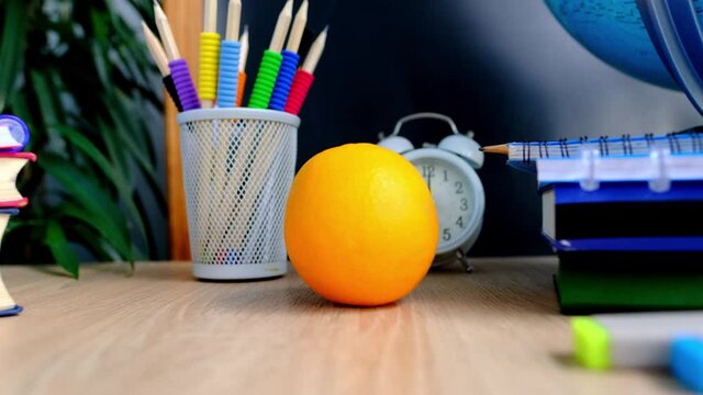student home office table with white alarm clock, books, orange, colored notebooks, pencils in glass, chalk board, globe, white alarm clock, concept of education, back to school, knowledge day