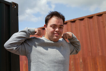 Young man with Down Syndrome in active wear flexing his muscles