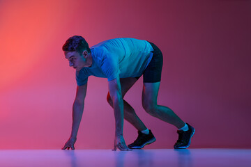 Portrat of Caucasian professional male athlete, runner training isolated on pink studio background...