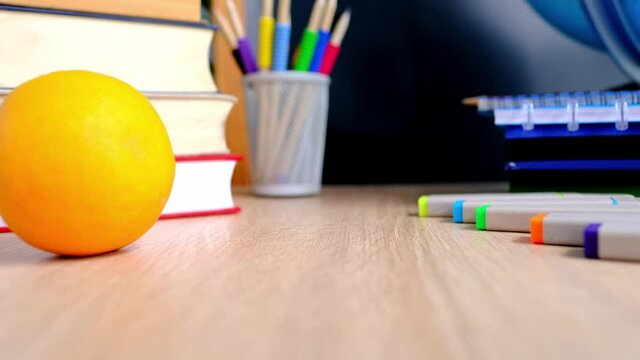 student home office table with white alarm clock, books, orange, colored notebooks, pencils in glass, chalk board, globe, white alarm clock, concept of education, back to school, knowledge day