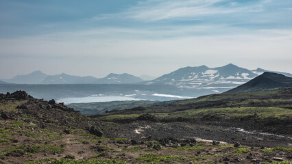 There is scant vegetation on the mountainside, volcanic rocks. In the distance, you can see a lake,...