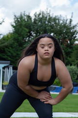 Young biracial woman with Down Syndrome in active wear stretching and looking confident