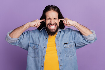 Portrait of a man close ears grind teeth irritated close eyes avoid noise on purple wall