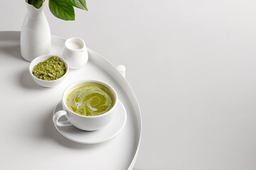Green matcha tea with milk in cup on white table and white backgriund