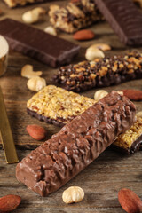 Different tasty protein bars and nuts on wooden table