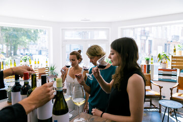 Young female friends doing wine degustation indoor at bar restaurant - People drinking and smelling wine concept