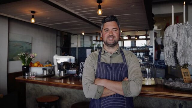 Handsome waiter standing cross-armed in funky cafe. 