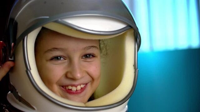 Child plays at home in an astronaut,portrait funny of a little girl 8-9 years old in a toy space helmet,smiling child looking at camera,close-up,pilot traveling into space.Concept of a happy childhood