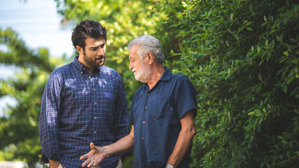 Adult hipster son and old senior father stay for work at home, two generations have a beard talking...