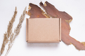 Brown flat cardboard carton box decorated with dried leaves, top view