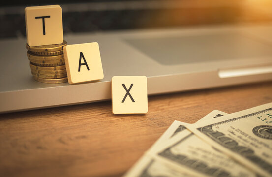 TAX text on business desk with laptop and dollar bills. Banking revenue concept background photo