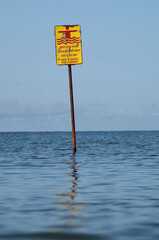 a yellow sign into ocean water