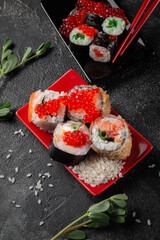 Sushi roll with reflection on a black background. A restaurant with Japanese cuisine. Women's hands holding sushi rolls.