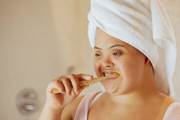 Young biracial woman with Down Syndrome brushing her teeth with bamboo toothbrush