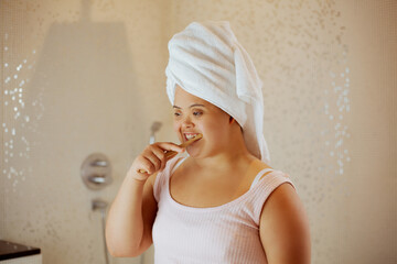 Young biracial woman with Down Syndrome brushing her teeth with bamboo toothbrush