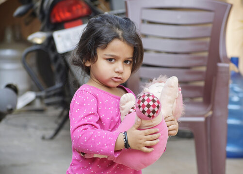 Closeup Of A Cute Little Girl In A Pink Shirt Holding A Toy.