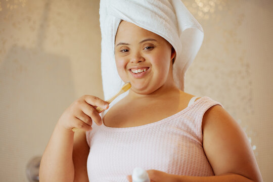 Young biracial woman with Down Syndrome brushing her teeth with bamboo toothbrush