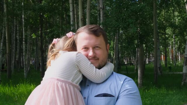 Happy father carrying around his neck and hugging daughter 4-5 years old while walking in the park