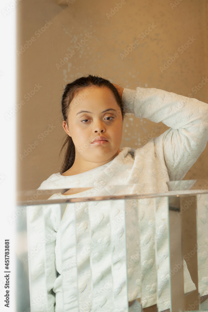 Wall mural Young biracial woman with Down Syndrome tying her hair in the bathroom