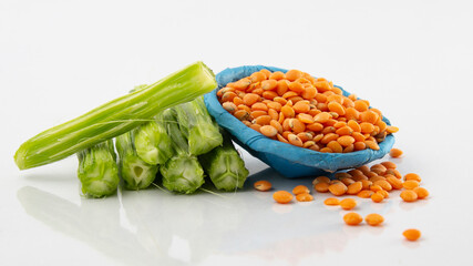 A heap of peeled Fresh green Pods of Moringa oleifera, horseradish, drumstick tree, Isolated on a white background with lentil Dal. it has great medicinal properties and health benefits.