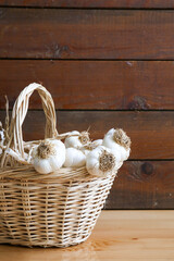 a basket of dried garlic in front of a wooden background, writing area