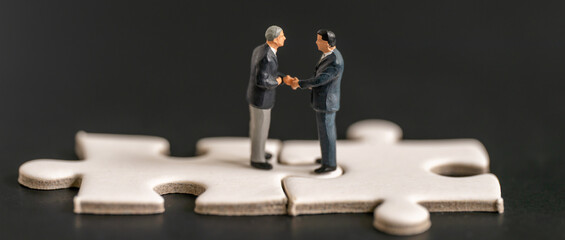 Miniature business man shake hand partner client customers on white Jigsaw Puzzle with success dealing business using as contract commitment agreement investment and partnership business development