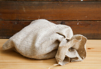 a tied linen sack in front of a wooden backdrop
