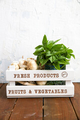 bunch of fresh basil and garlic in a decorative vegetable crate in front of white